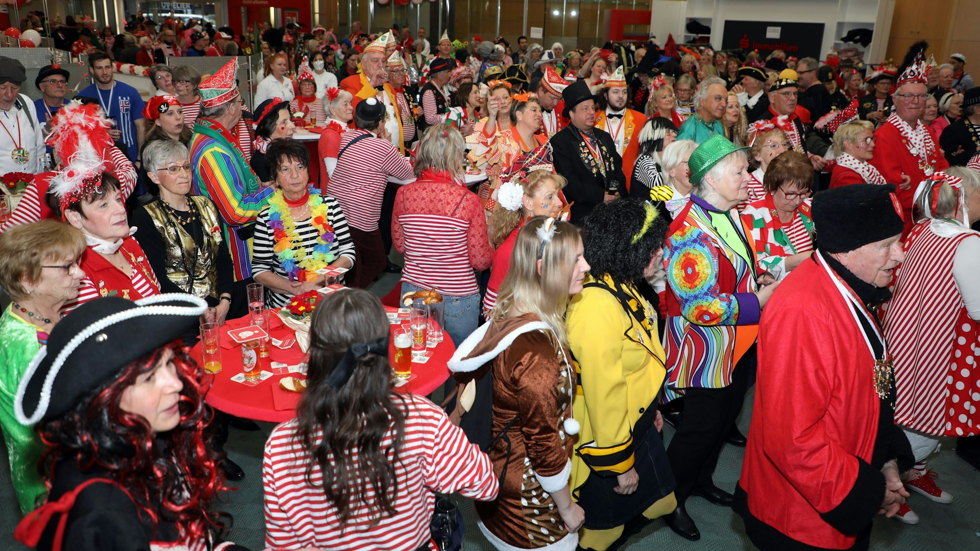 Kostümierte Menschen feiern am Weiberfastnachtstag 2023 in einer Halle Karneval.