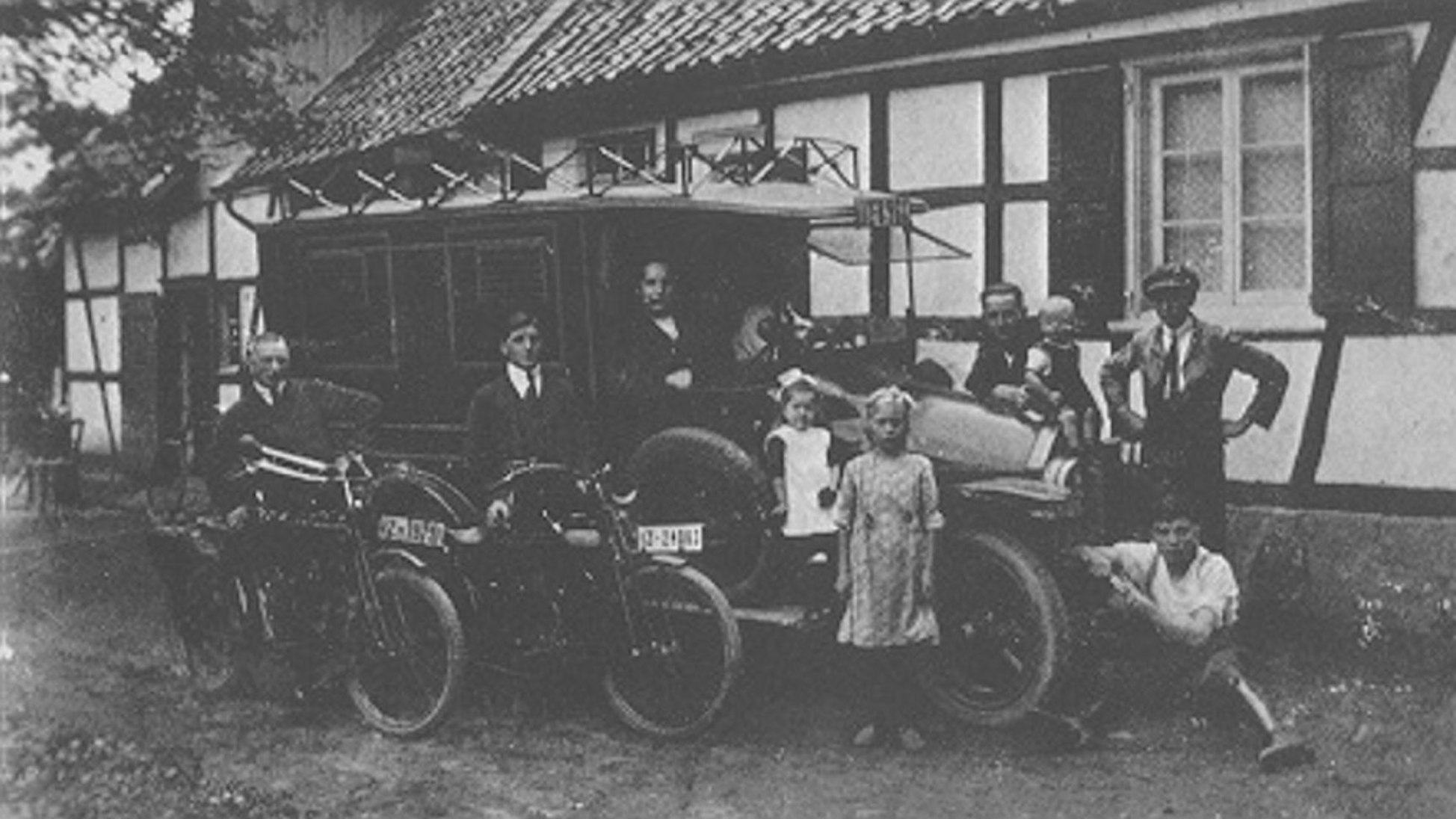 Ein schwarz-weiß Bild zeigt einen alten Bus und einen Teil der Familie Wiedenhoff.