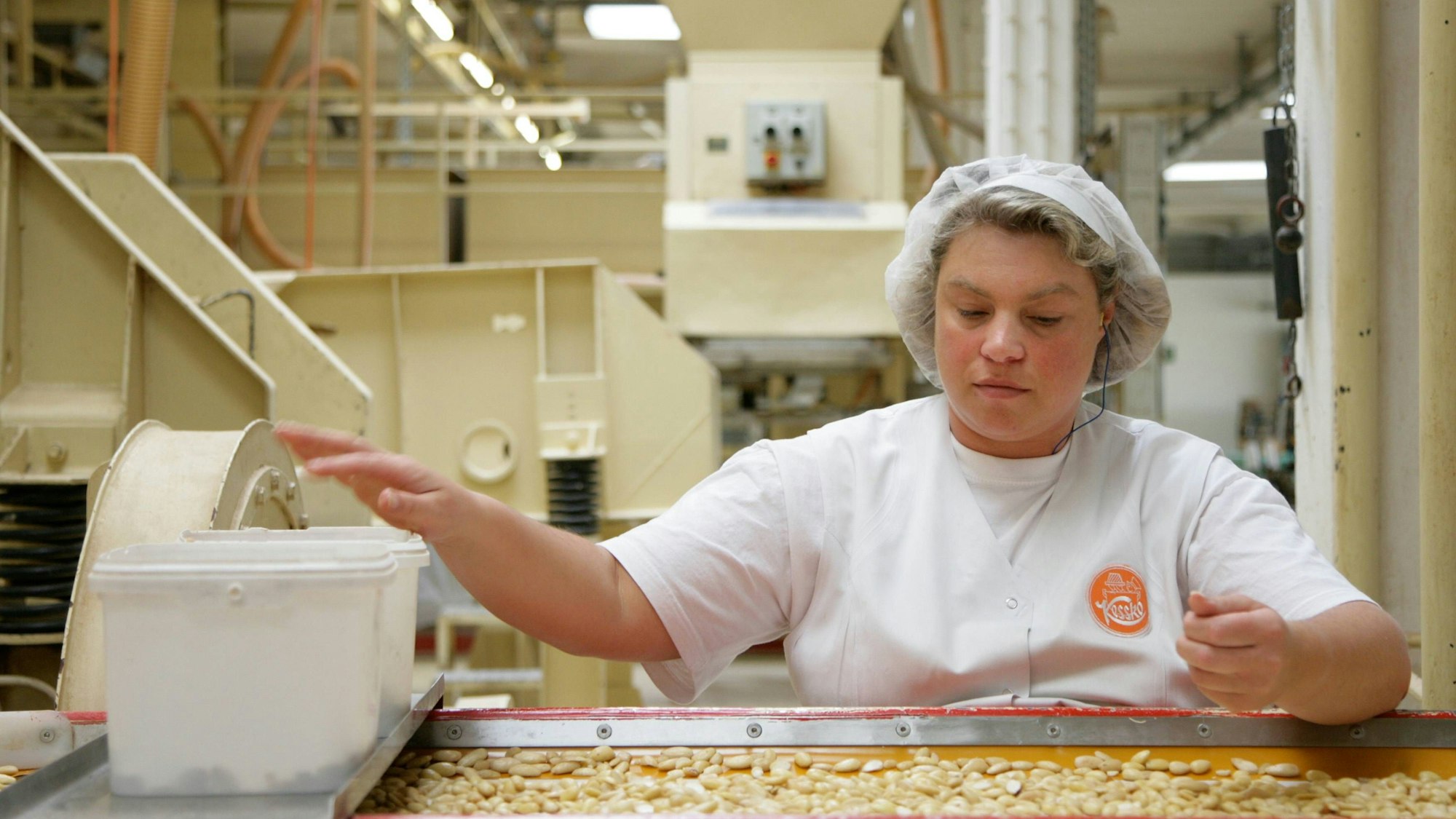 Eine Frau sortiert auf einem älteren Bild Erdnüsse in einer Fabrikhalle von Kessko. (Archivbild)
