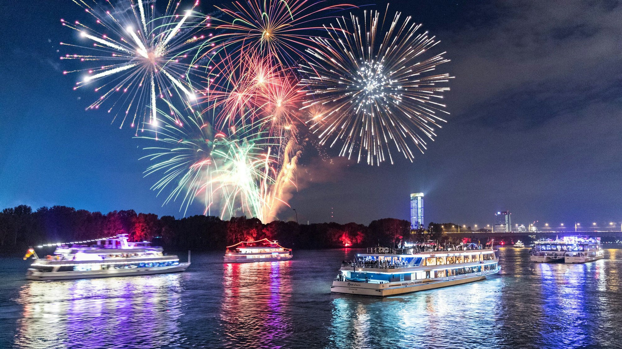 Von einem Schiffskonvoi auf dem Rhein in Bonn werden Feuerwerksraketen abgefeuert.