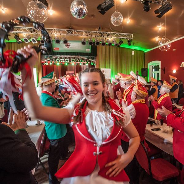 Das Kindertanzcorps der Roten Funken zieht tanzend und feiernd durch einen Sitzungssaal.