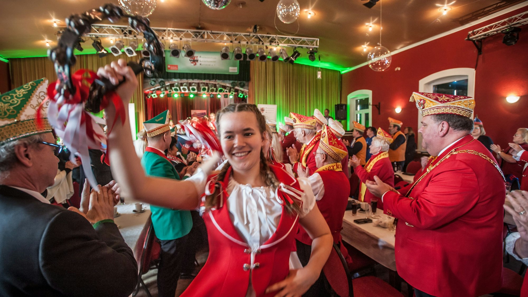 Das Kindertanzcorps der Roten Funken zieht tanzend und feiernd durch einen Sitzungssaal.