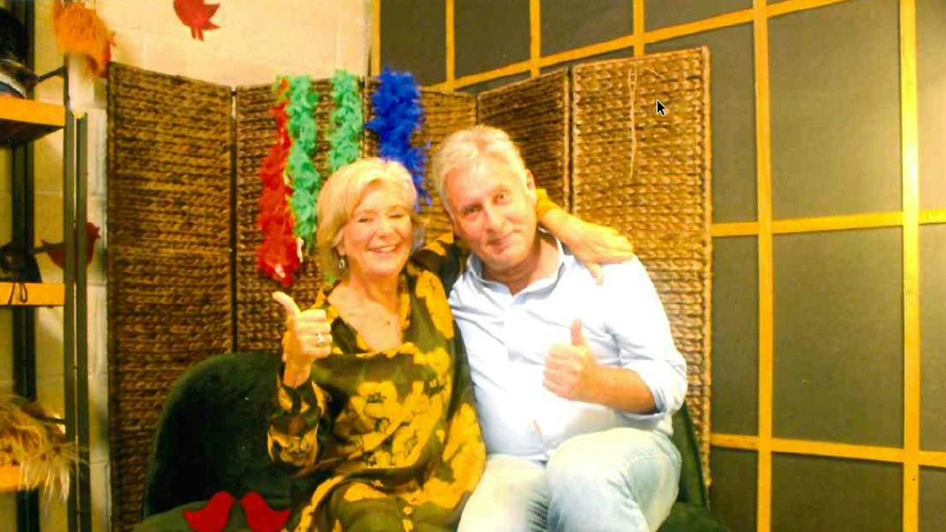 Ein Mann und eine Frau schießen ein Foto in einer Fotobox. Beide zeigen mit dem Daumen nach oben.