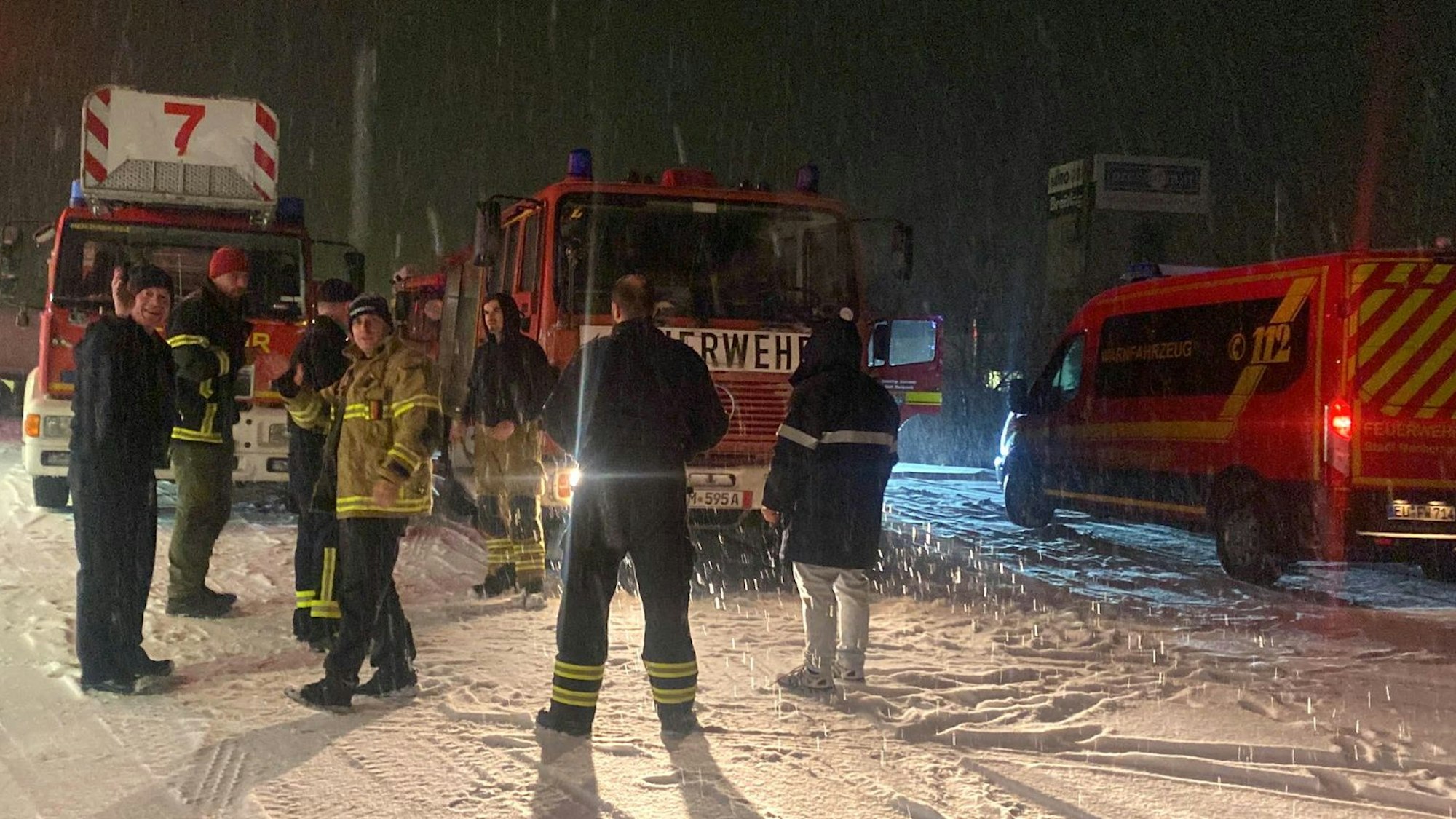 Aktive der Freiwilligen Feuerwehr Mechernich und der Gruppe Sophie aus Frechen bei einer Pause während ihrer Fahrt in die Ukraine. Es ist dunkel und es schneit.