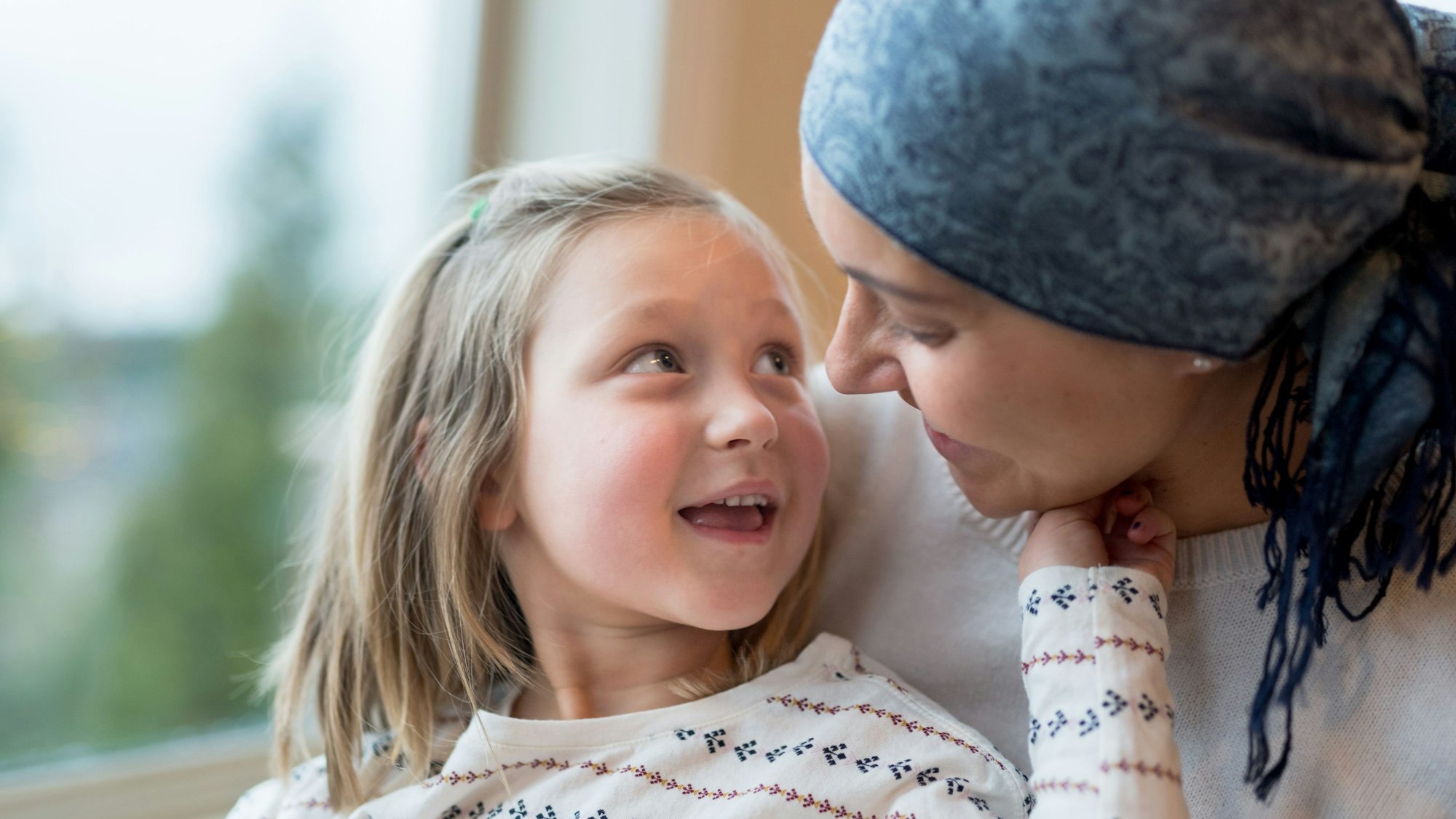 Ein kleines Mädchen sitzt bei einer Frau mit Kopftuch auf dem Schoß
