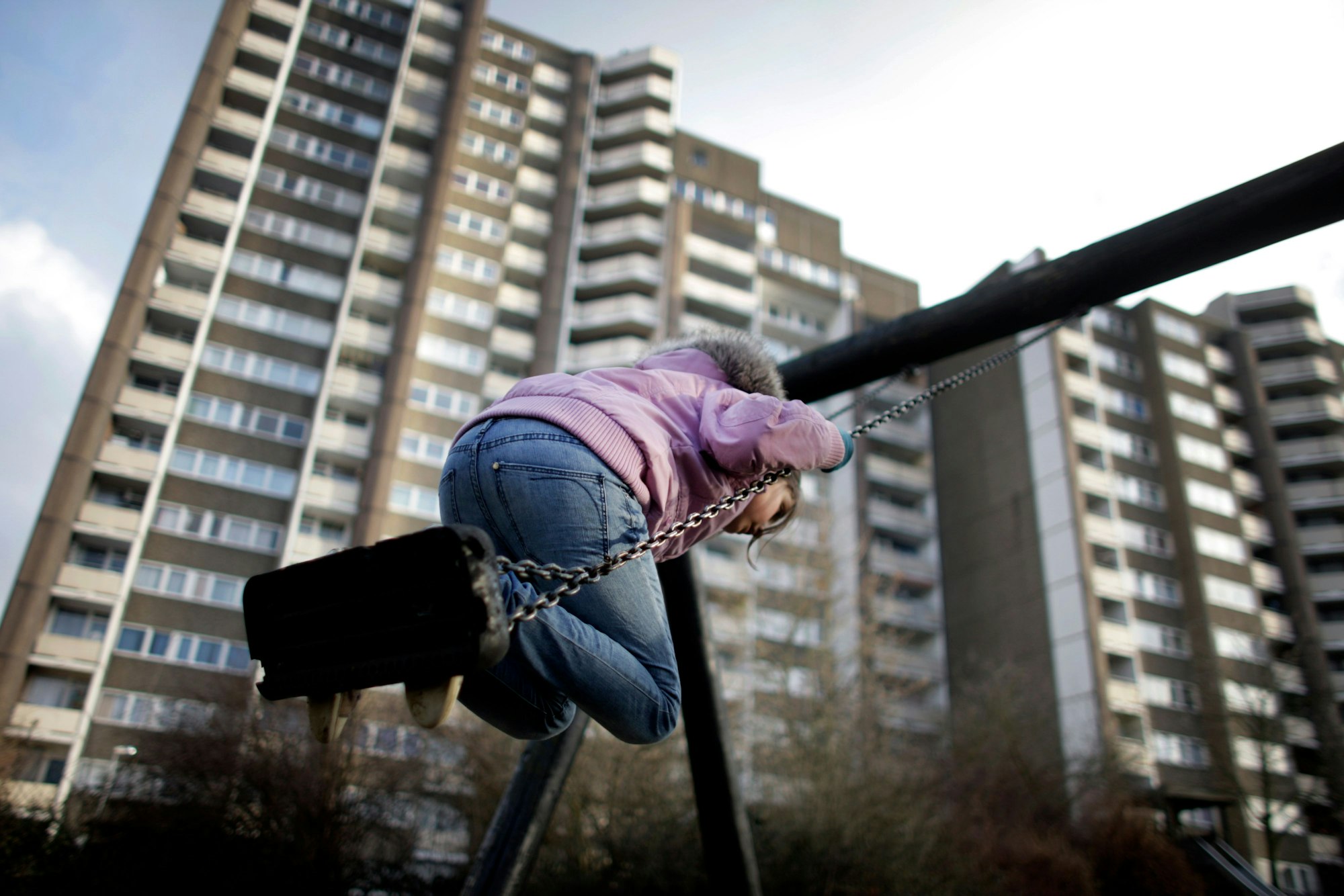 Ein Kind schaukelt vor einem Hochhaus in Meschenich bei Köln.