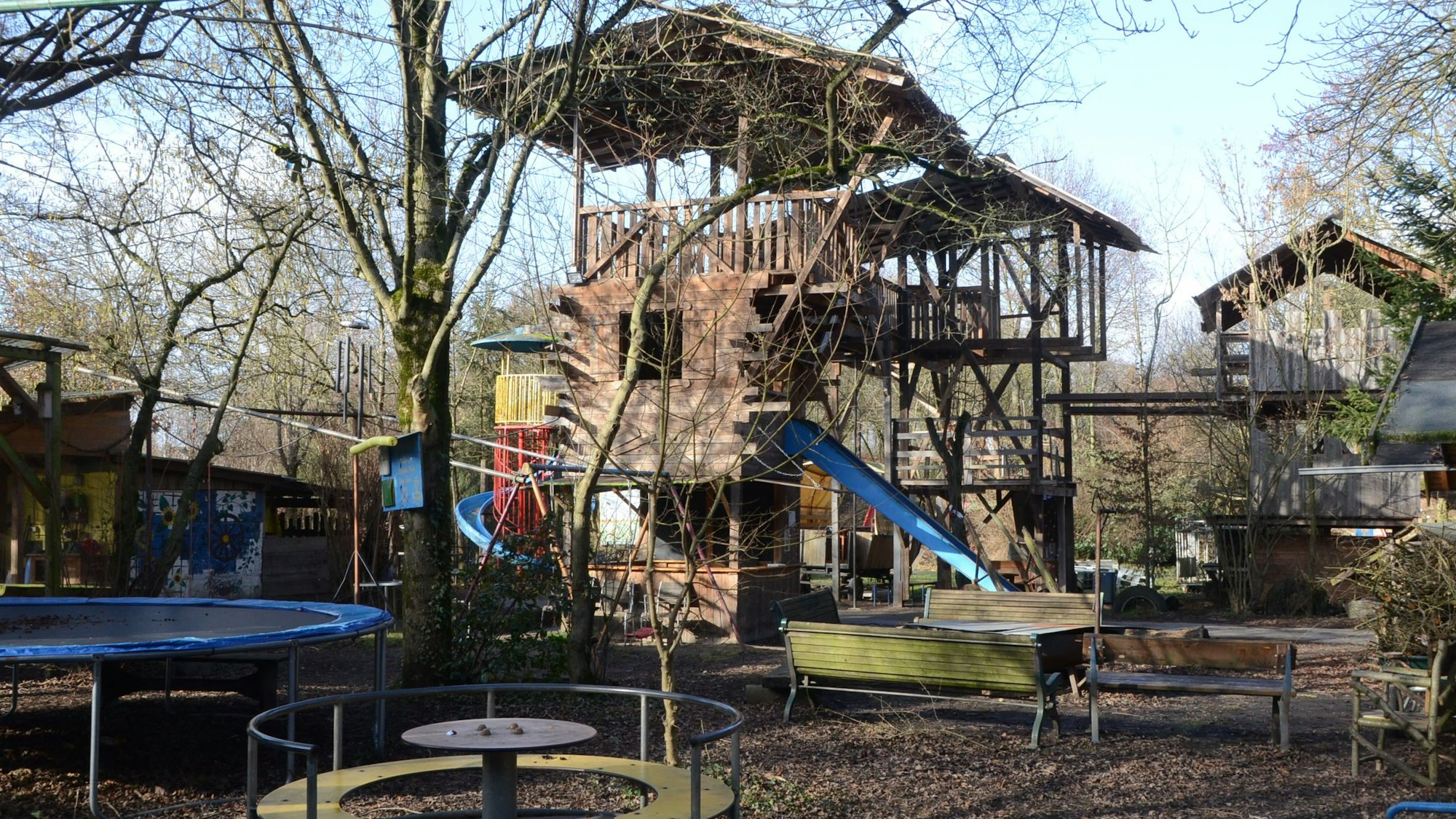 Türme aus Holz, Trampoline, Rutsche und andere Spielgeräte auf einem Freigelände.