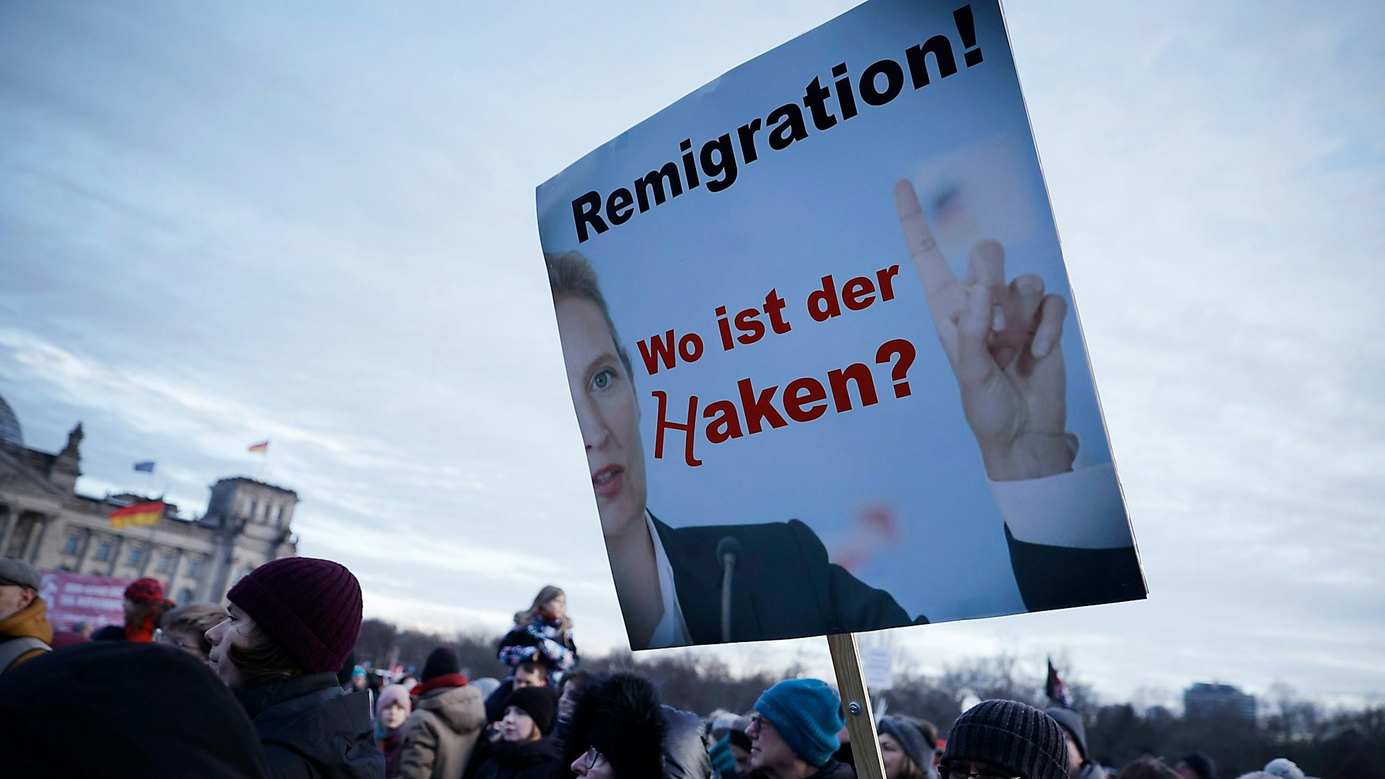 Demonstranten nehmen an einer Protestveranstaltung gegen Rechtsextremismus teil. Zu lesen ist ein Schild mit der Aufschrift "Remigration! Wo ist der Haken?"