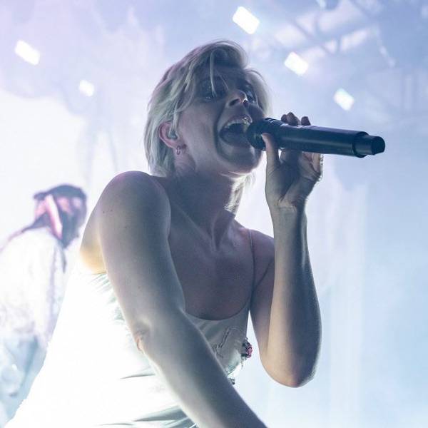 Die schwedische Sängerin Robyn im Jahr 2019 auf der Bühne des Kölner Palladiums. Sie trägt ein silbernes Negligé und singt in ein Mikrofon.