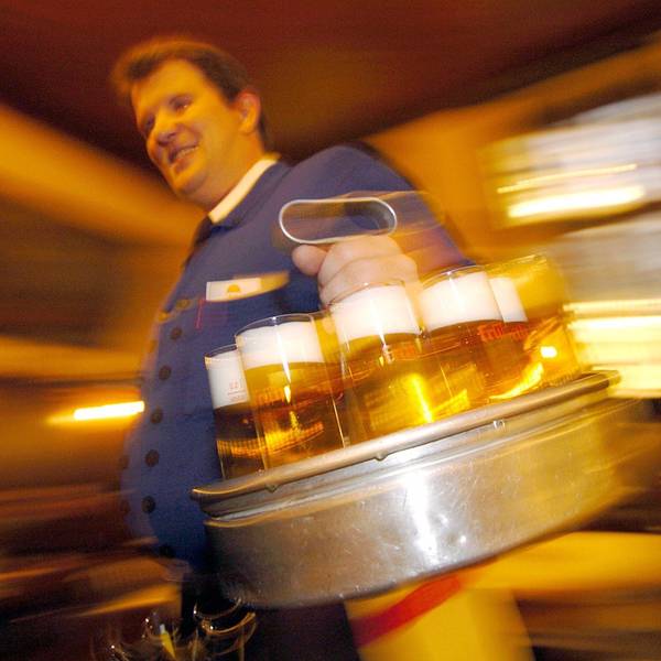 Ein Köbes in einem Kölsch-Brauhaus in der Kölner Innenstadt serviert Kölsch.