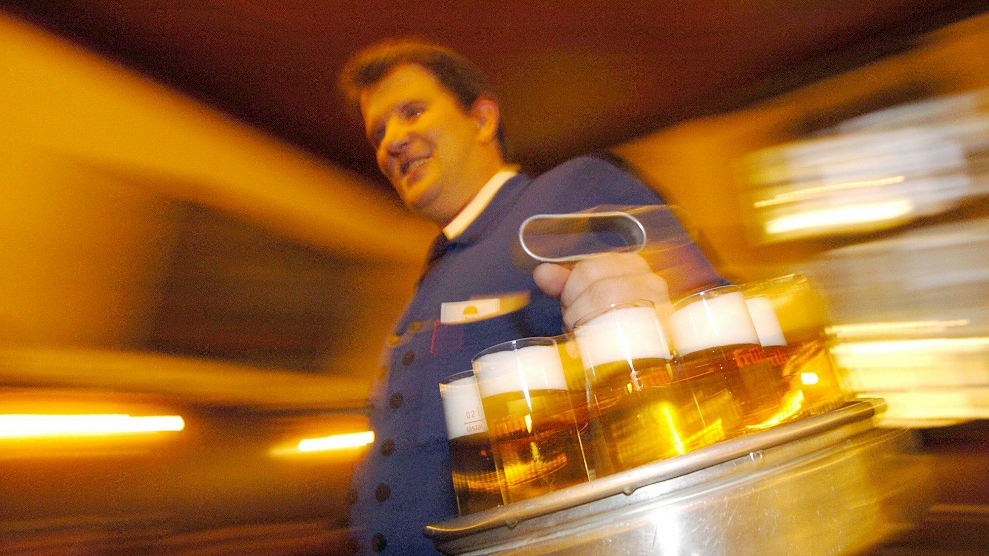 Ein Köbes in einem Kölsch-Brauhaus in der Kölner Innenstadt serviert Kölsch.