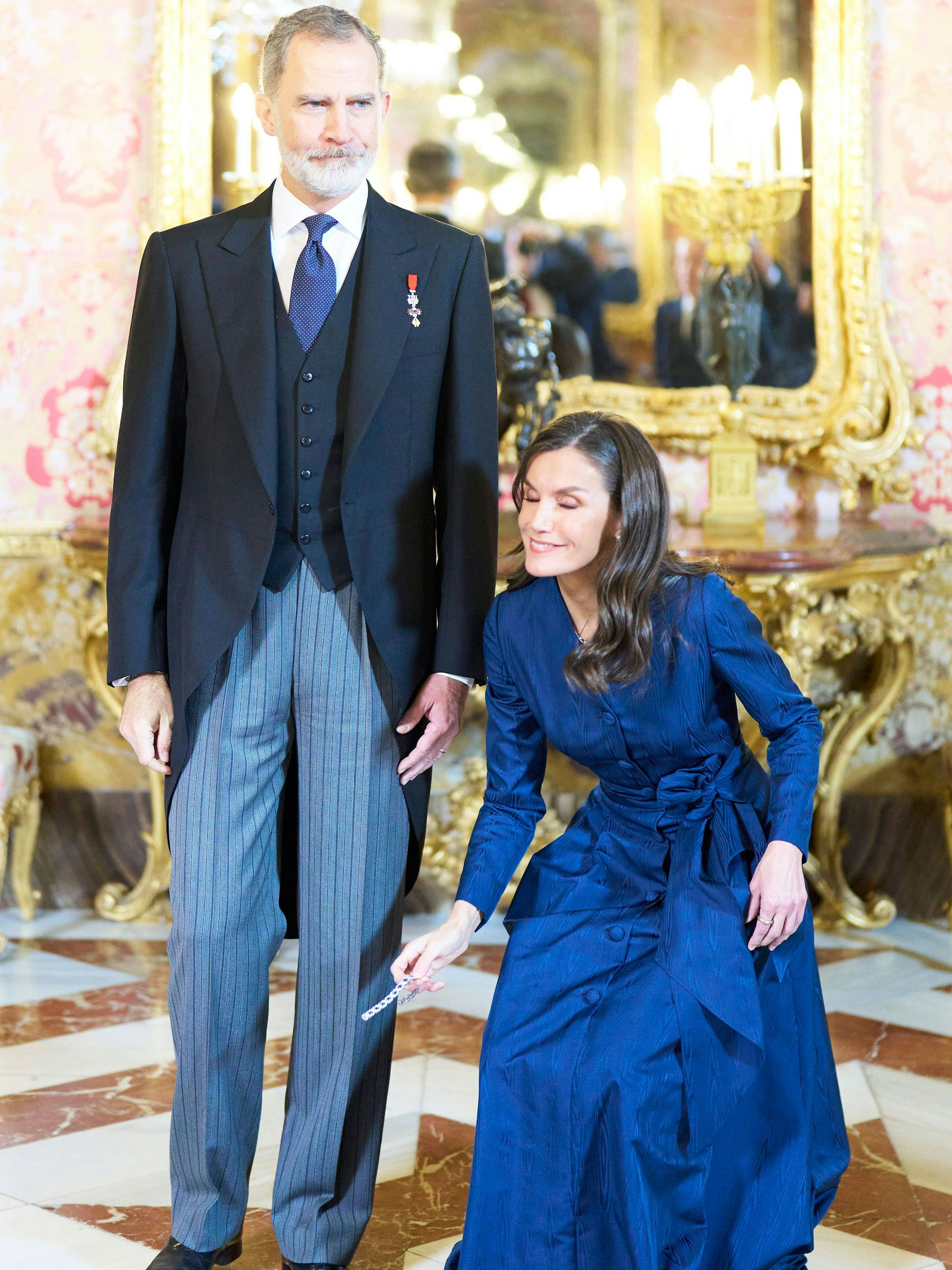 Königin Letizia hebt ihr Armband auf. Neben ihr König Felipe.