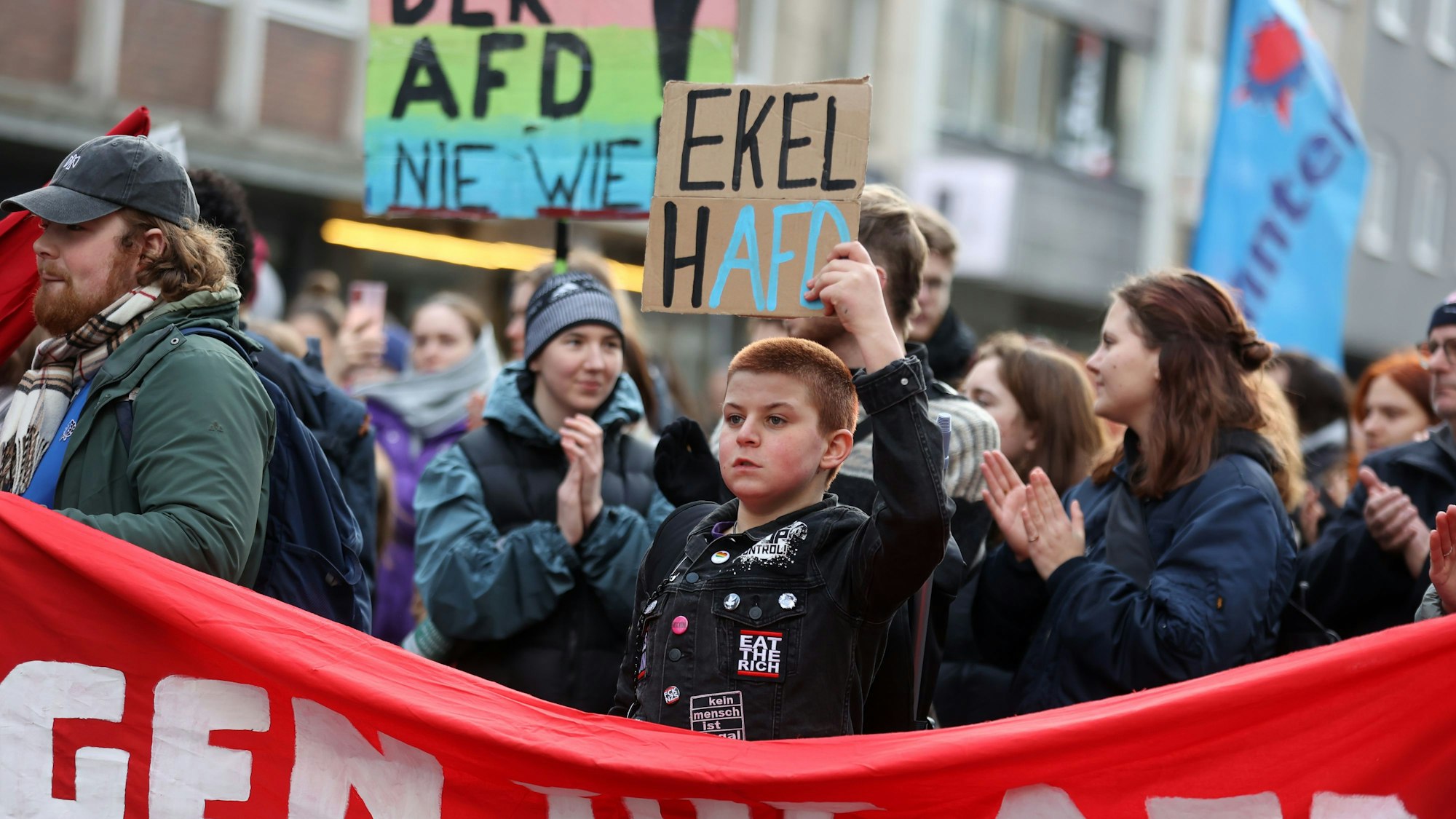 Ein Mann hält ein Pappschild auf einer Demo in die Luft.