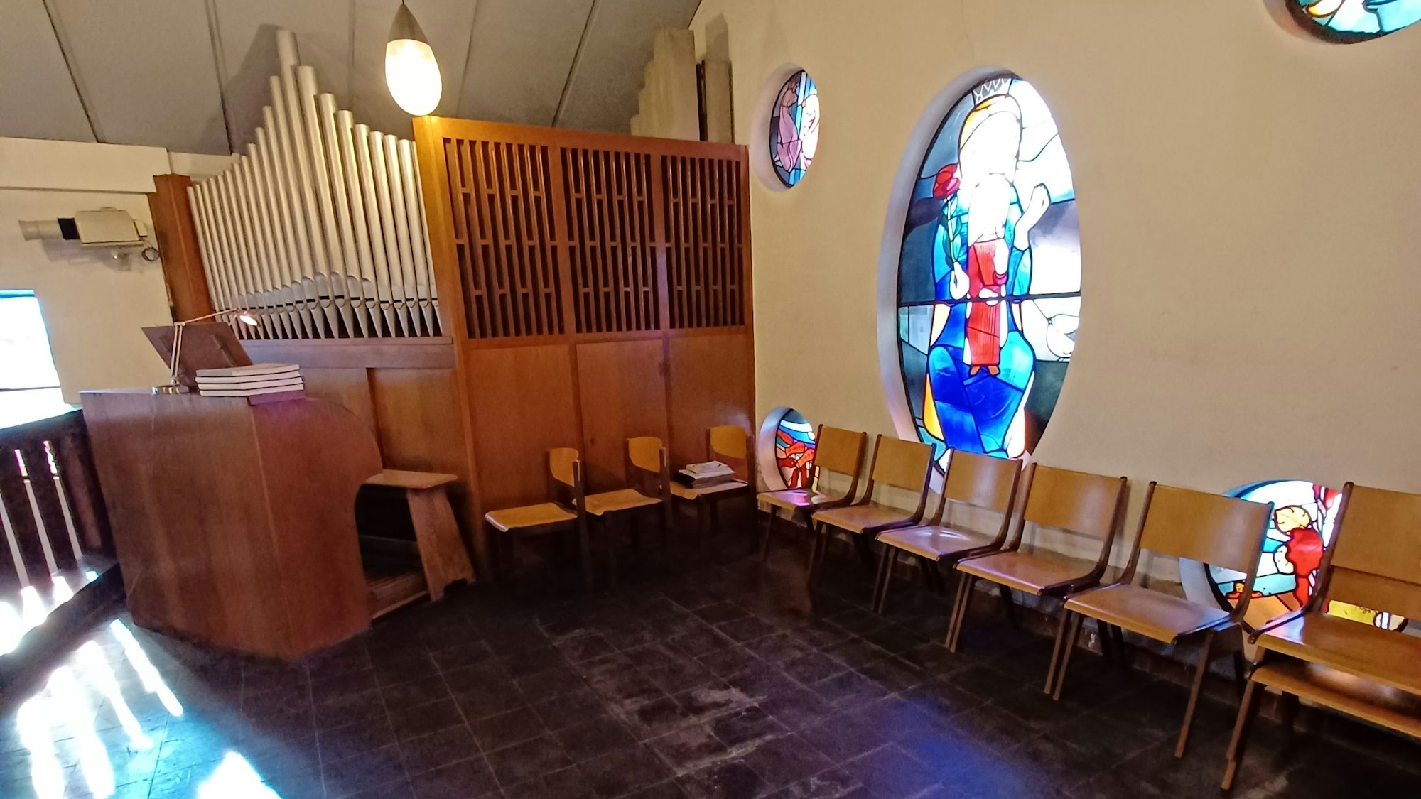 Zu sehen ist die Orgel-Empore in einer Kirche, an einer Wand stehen Stühle.