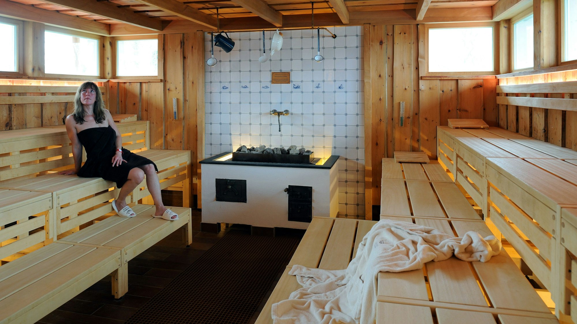 Eine junge Frau sitzt allein in der Strandhallen-Sauna im „BadeWerk“ von Neuharlingersiel.