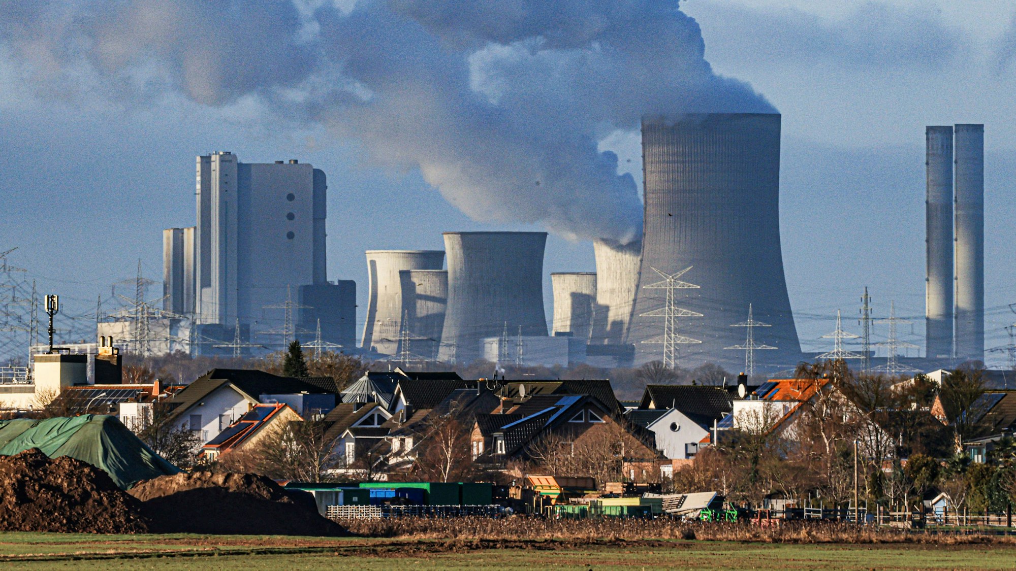 01.02.2024, Nordrhein-Westfalen, Pulheim: Dampf steigt aus dem RWE Braunkohlekraftwerk Niederaußem. Im Vordergrund der Pulheimer Ortsteil Sinnersdorf. Das Kraftwerk Niederaußem ist ein von RWE Power mit Braunkohle betriebenes Grundlastkraftwerk. Ein Teil der Blöcke des Kraftwerkes wurden stillgelegt. Foto: Oliver Berg/dpa +++ dpa-Bildfunk +++