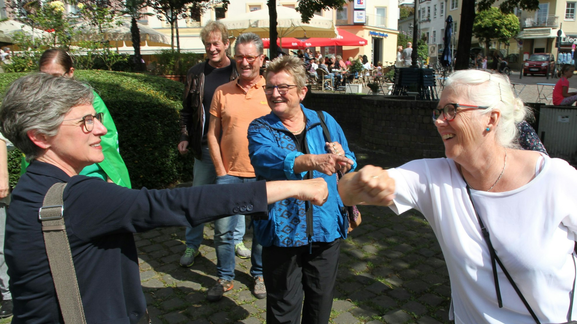 Zwei Frauen strecken sich zur Begrüßung Faust und Ellbogen entgegen