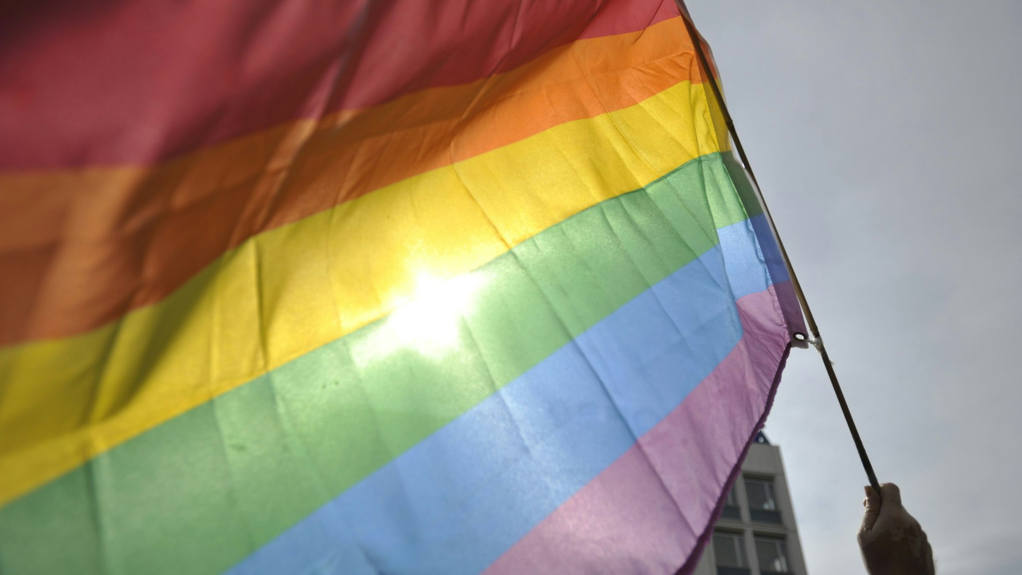 Eine Person hält eine Regenbogenflagge vor der russischen Botschaft in Berlin. Queere Menschen erfahren in Russland massive Repressionen. (Symbolbild)