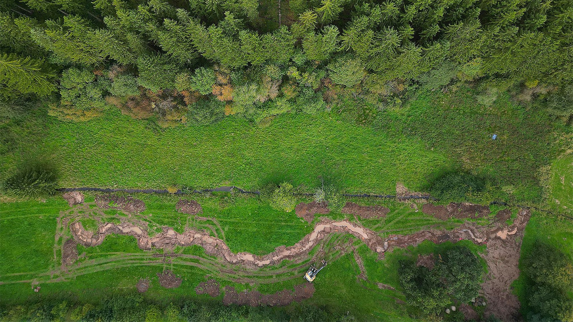 Das Luftbild zeigt einen renaturieren Abschnitt der Berke bei Dahlem: Der Bach schlängelt sich durch die Landschaft. Darüber ist in gerader Linie der vorherige Bachlauf zu erkennen.