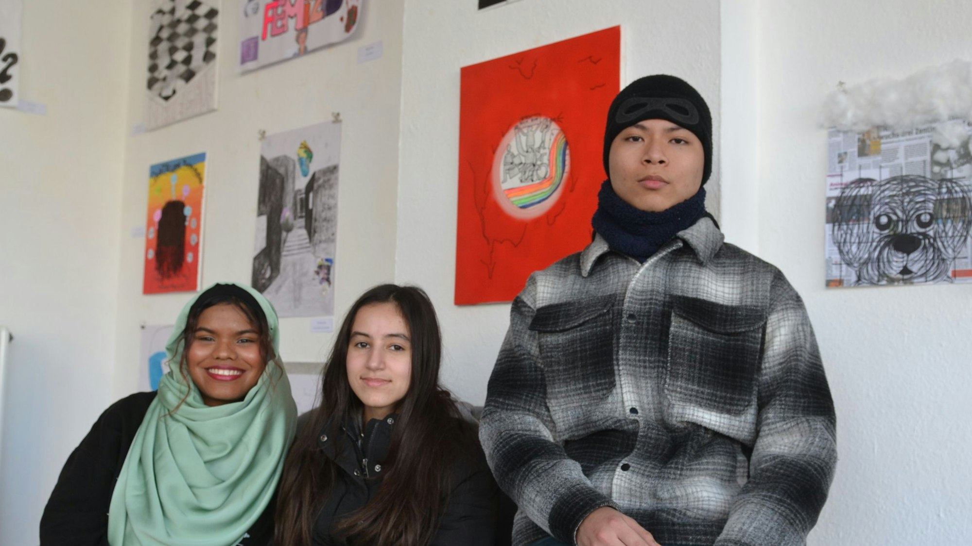 Schülerinnen und Schüler der Klasse EF der Gesamtschule Euskirchen sitzen vor ihren Bildern zum Thema „Gesicht zeigen“ in der Galerie FzKKE.