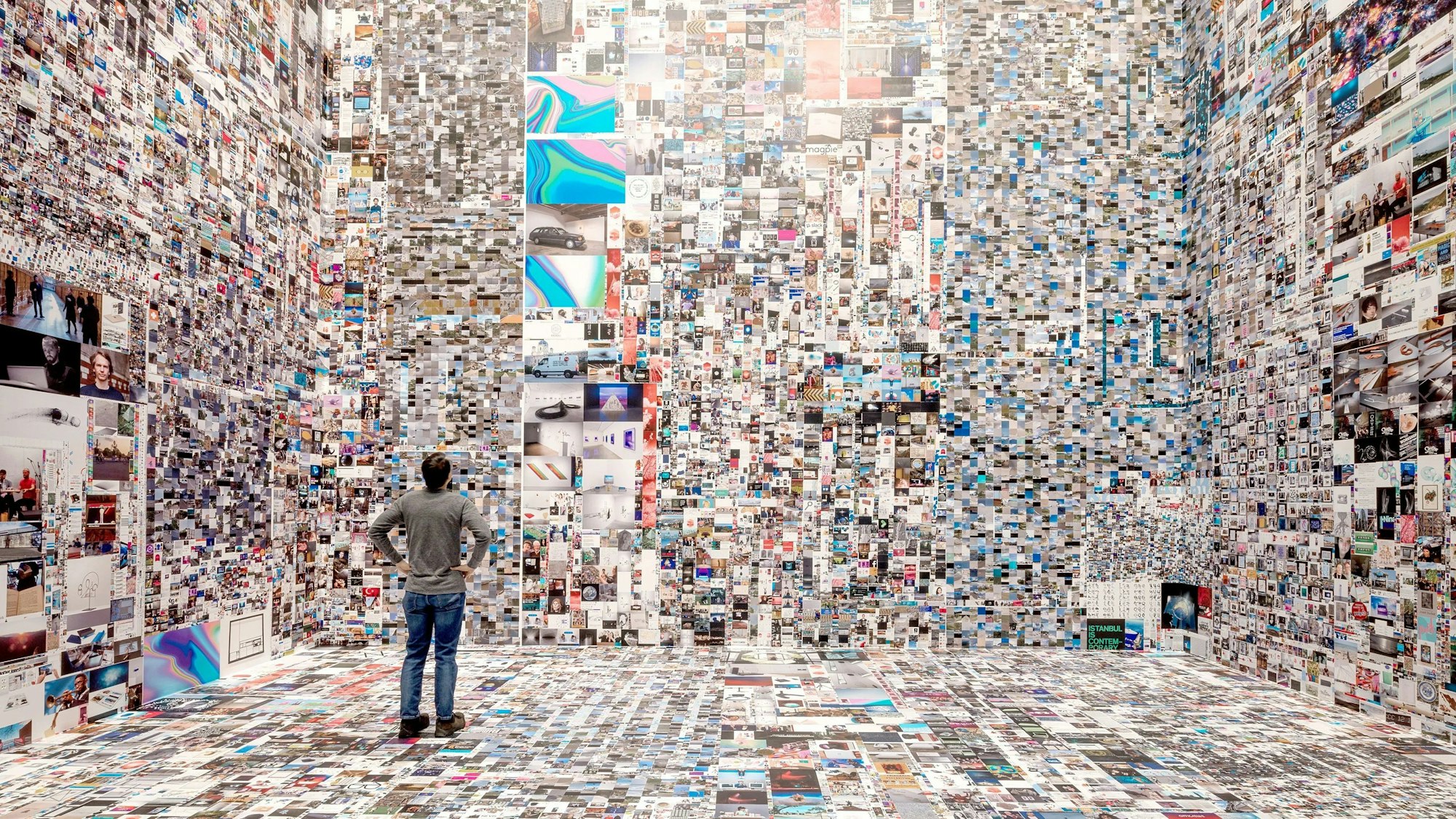 Ein Mann steht in einem mit Millionen Internetfotos tapezierten Raum.