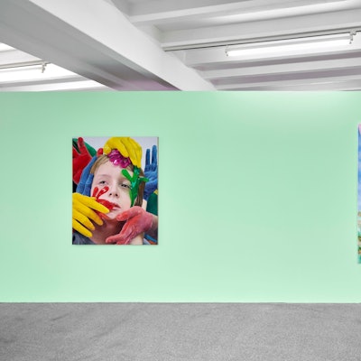 Zwei Bilder hängen an einer grünen Wand. Auf einem sind bei einem Mann Füße und Hände vertauscht.