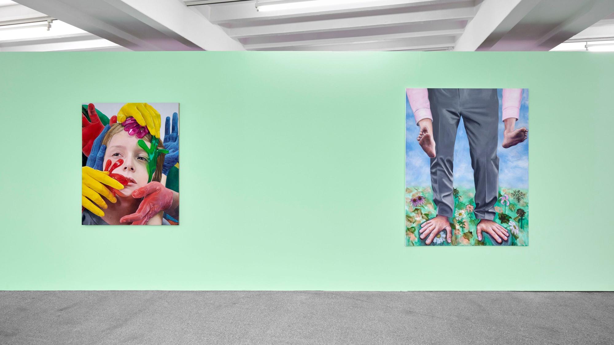 Zwei Bilder hängen an einer grünen Wand. Auf einem sind bei einem Mann Füße und Hände vertauscht.