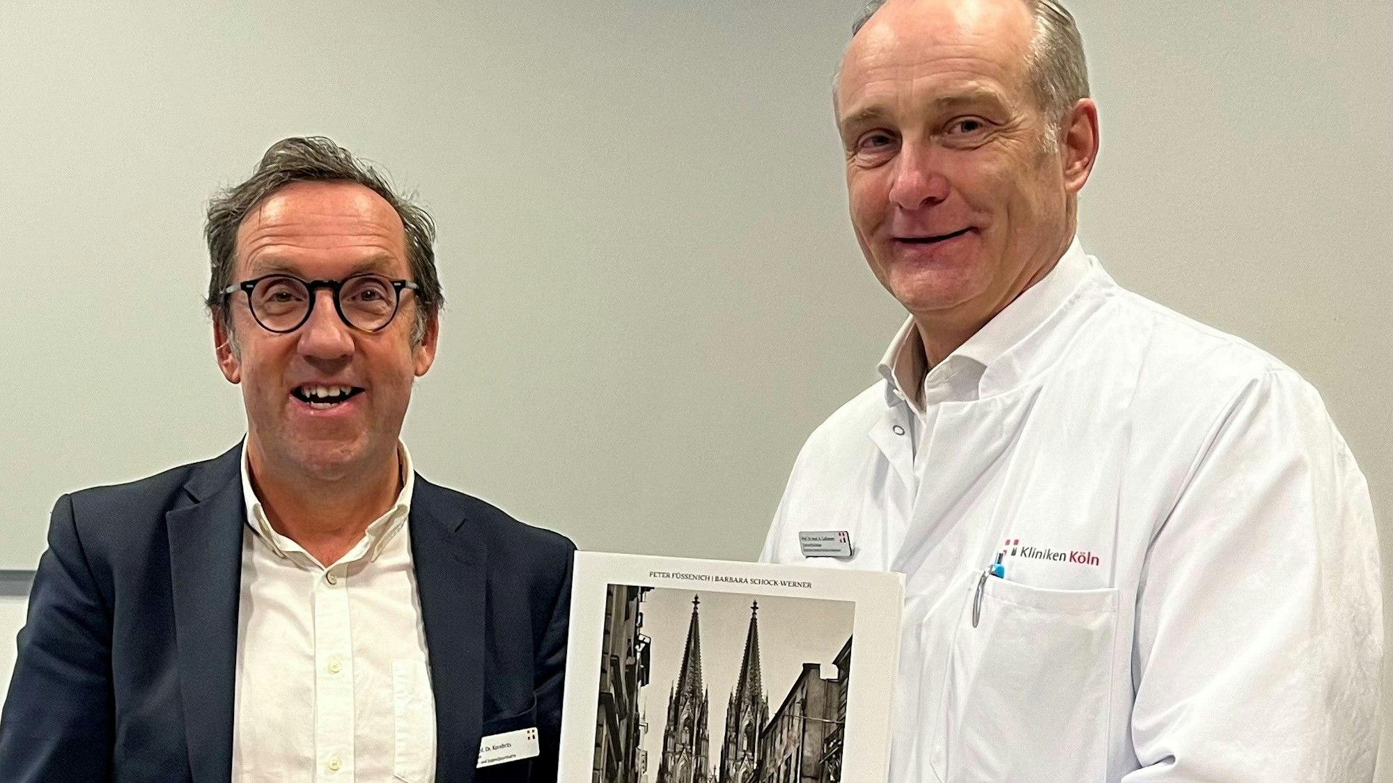Das Bild zeigt Herrn Prof. Dr. Korebrits (links) und Herr Prof. Dr. Goßmann (rechts) bei der Überreichung eines Buchpräsents zur Begrüßung.