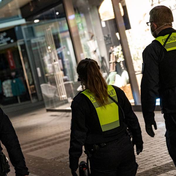 Ordnungsamtsmitarbeiter laufen in der Nacht eine Straße entlang.