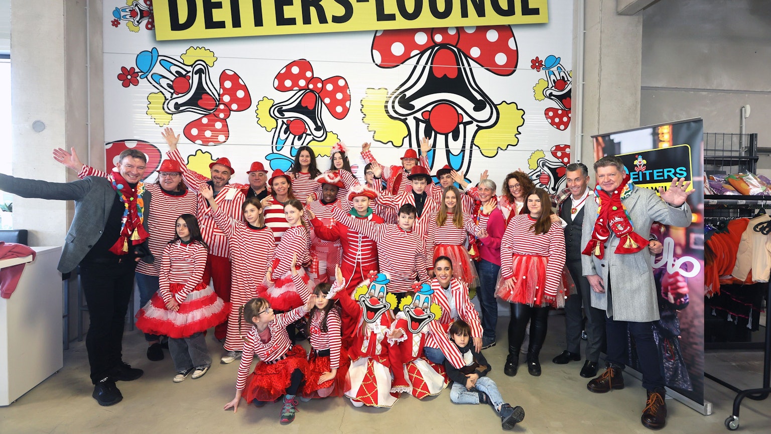 Bewohner und Betreuer der Brücker „KidS“-Wohnheime sind mit Kostümen in rot-weiß verkleidet und stehgen vor einer Wand der Deiters-Filiale in Frechen.