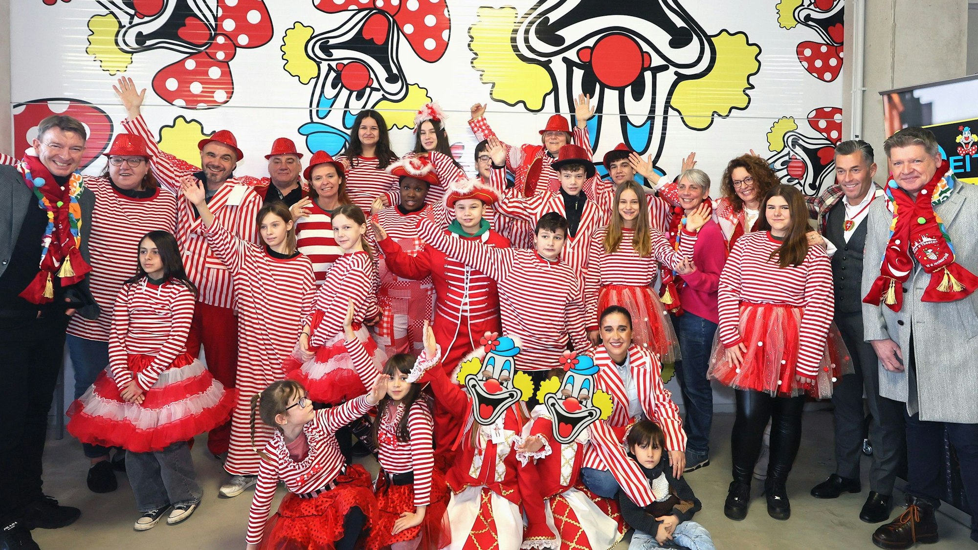 Bewohner und Betreuer der Brücker „KidS“-Wohnheime sind mit Kostümen in rot-weiß verkleidet und stehgen vor einer Wand der Deiters-Filiale in Frechen.