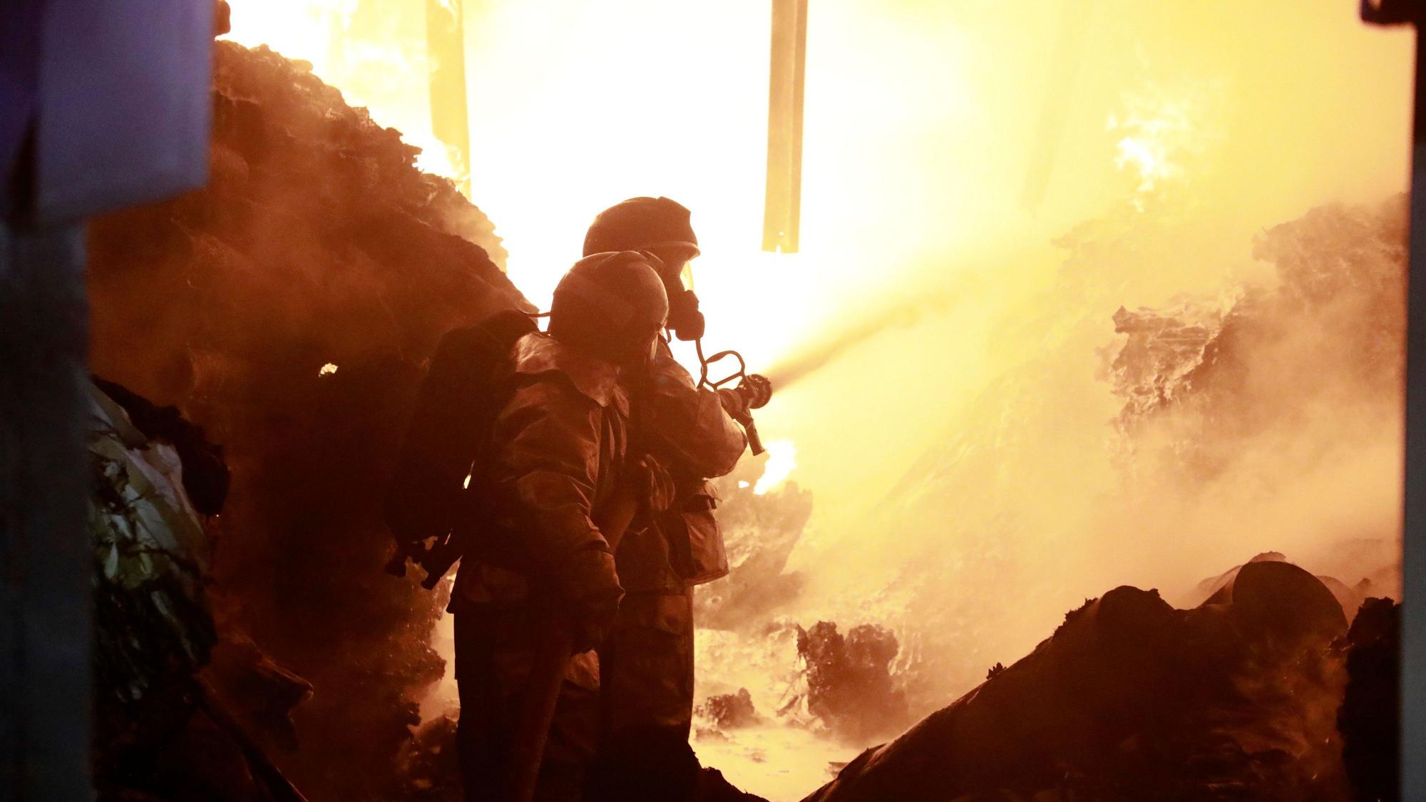 Feuerwehrleute löschen ein Feuer, das durch eine Explosion in einem Industriegebäude verursacht wurde.