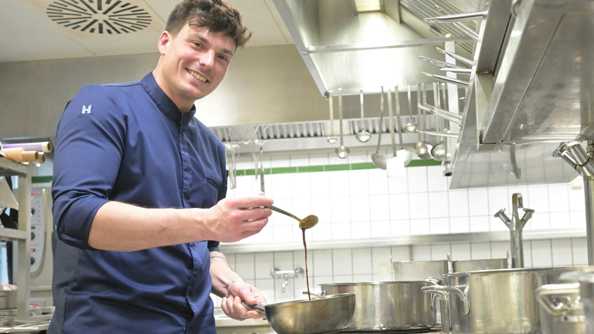 Küchenchef Christian Meinke schlägt eine Sauce auf.