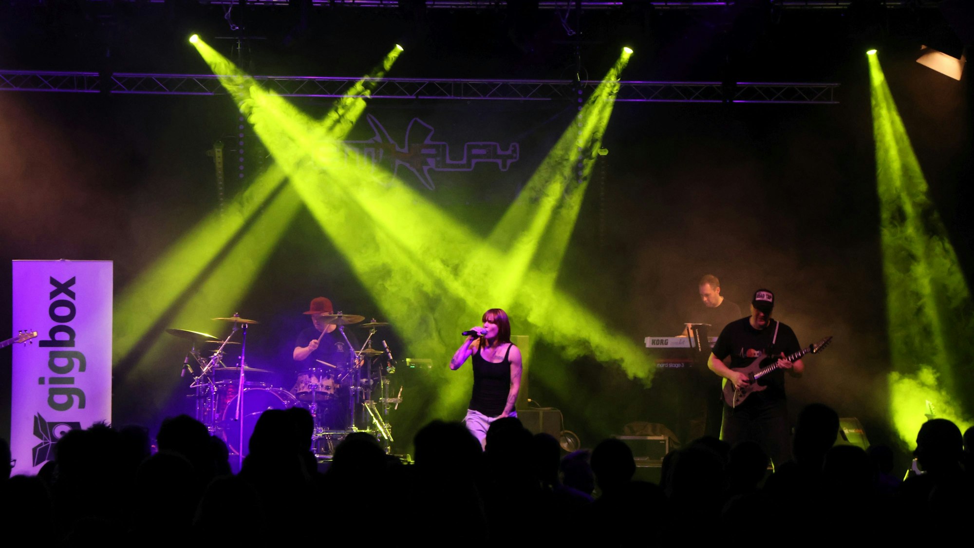 Eine Band im Scheinwerferlicht einer großen Bühne.