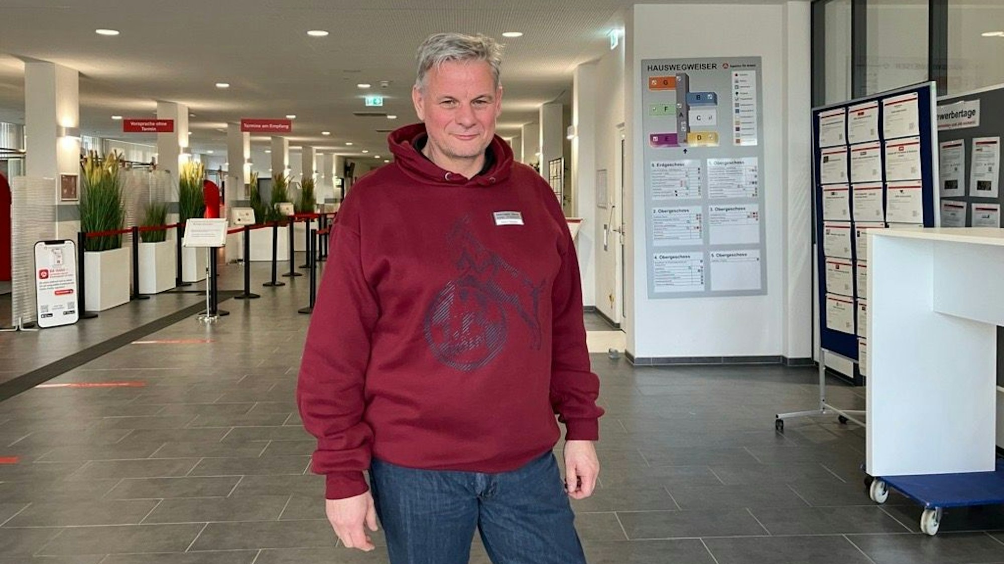 Torsten Heller leitet das Projekt zur schnellen Jobvermittlung der Agentur für Arbeit seit Mai 2022. ER steht im FC-Pullover im Eingangsbereich der Agentur am Butzweilerhof.