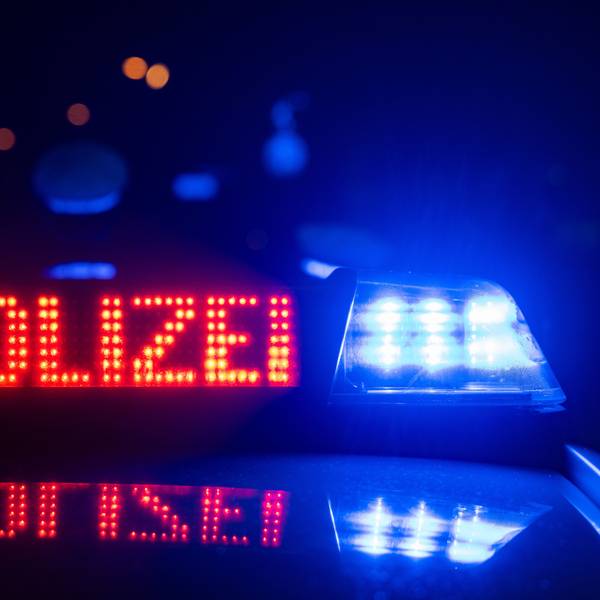 Eine Polizeischrift leuchtet neben einem Blaulicht an einem Abend auf einem Polizeiwagen.