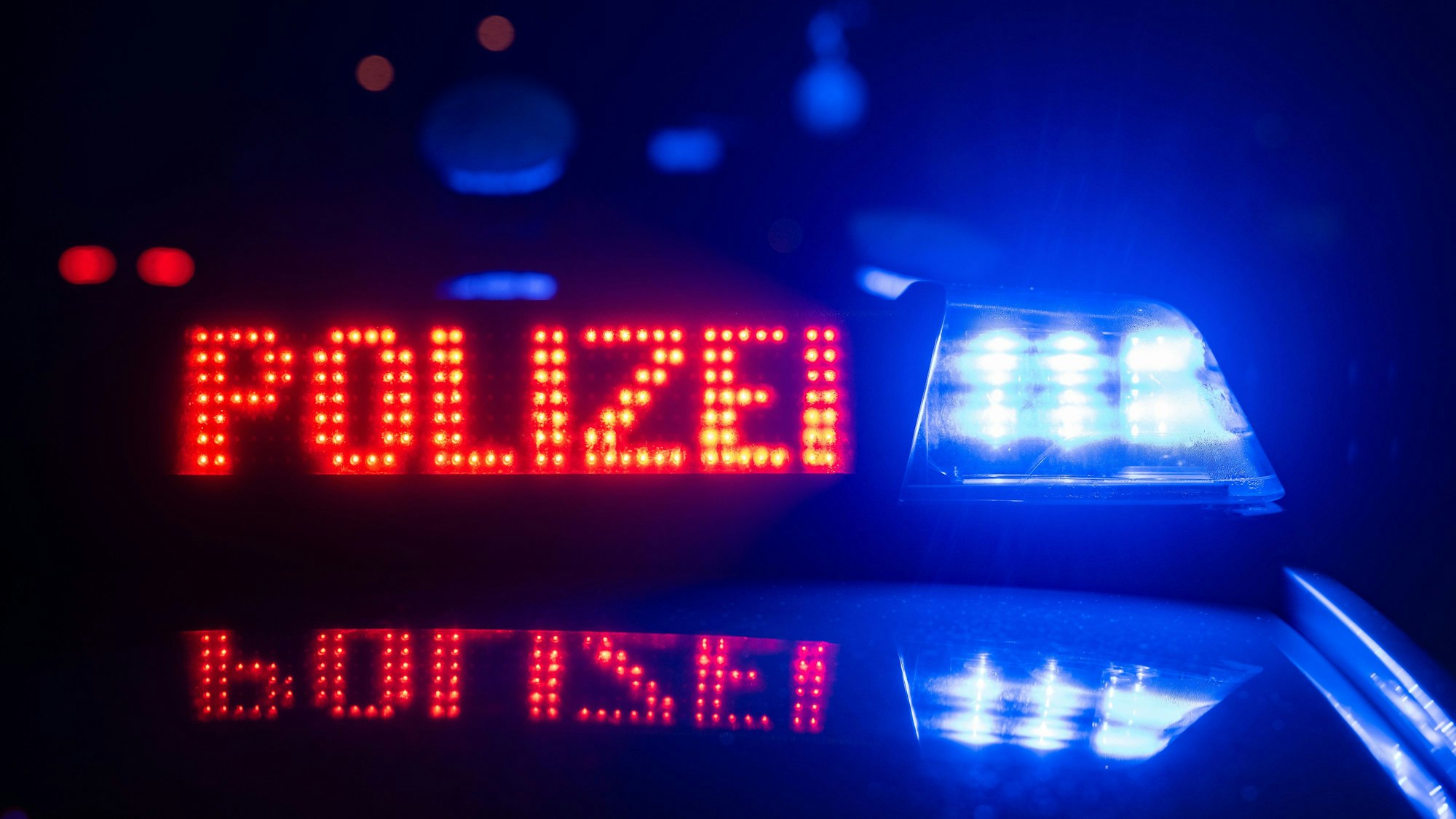 Zu sehen ist die rote Aufschrift „Polizei“ auf einem Polizeifahrzeug.