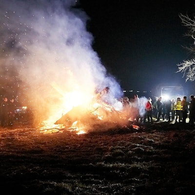 Zahlreiche Menschen stehen an einem größeren Mahnfeuer.