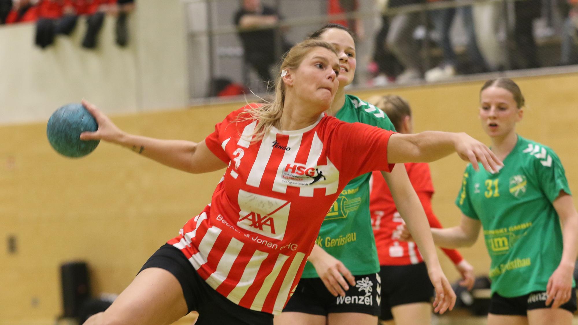 Sabine Schmitz springt mit Willen und Zuversicht zum Torwurf. Ihr Ohr-Piercing ist abgeklebt. Den blauen Ball streckt sie vom Körper weg, um auszuholen.
