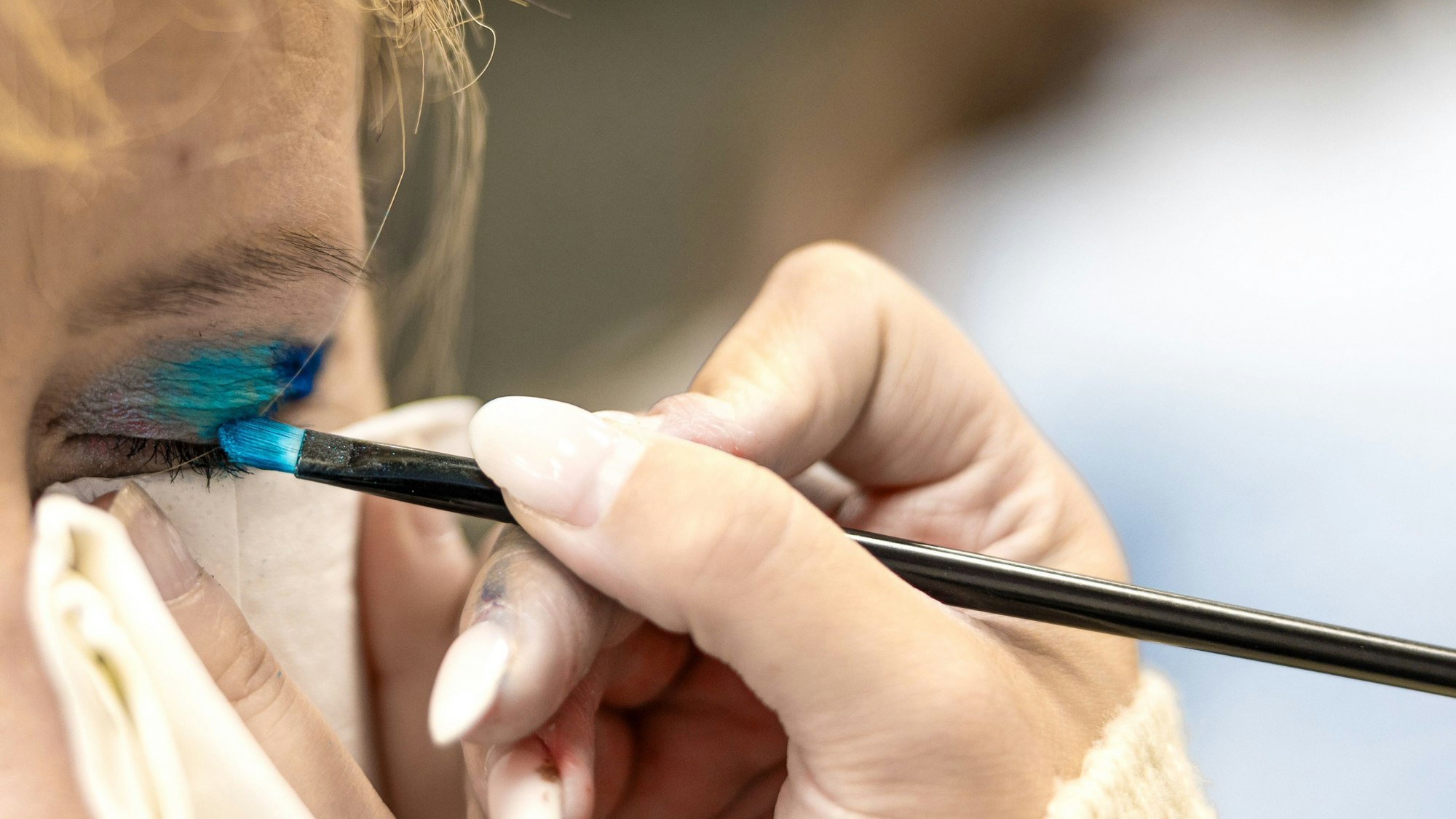 Ein Funkenmariechen schminkt einem anderen die Augen.