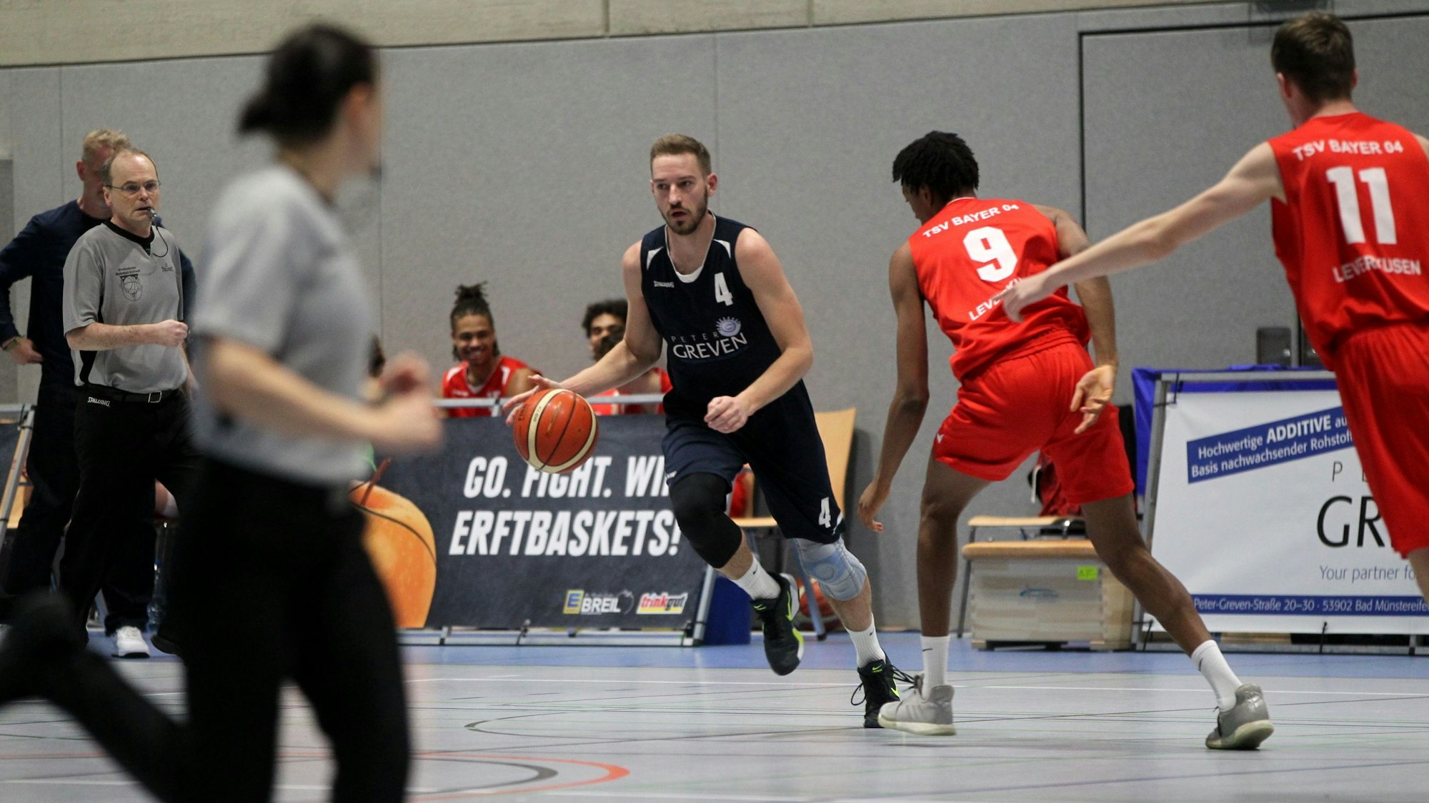 Jan Winkelnkemper dribbelt mit dem Ball. Im Vordergrund sind unscharf die Schiedsrichter zu erkennen.