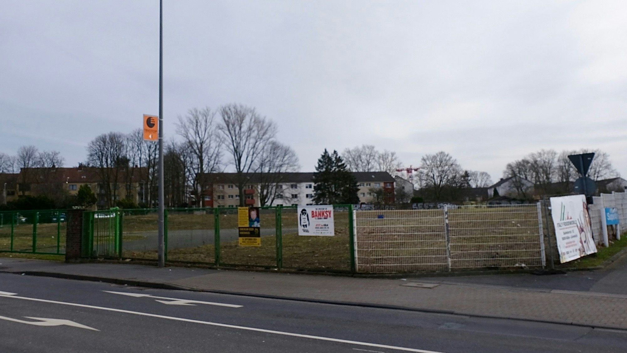 An einer Straße liegt eine große unbebaute Fläche.