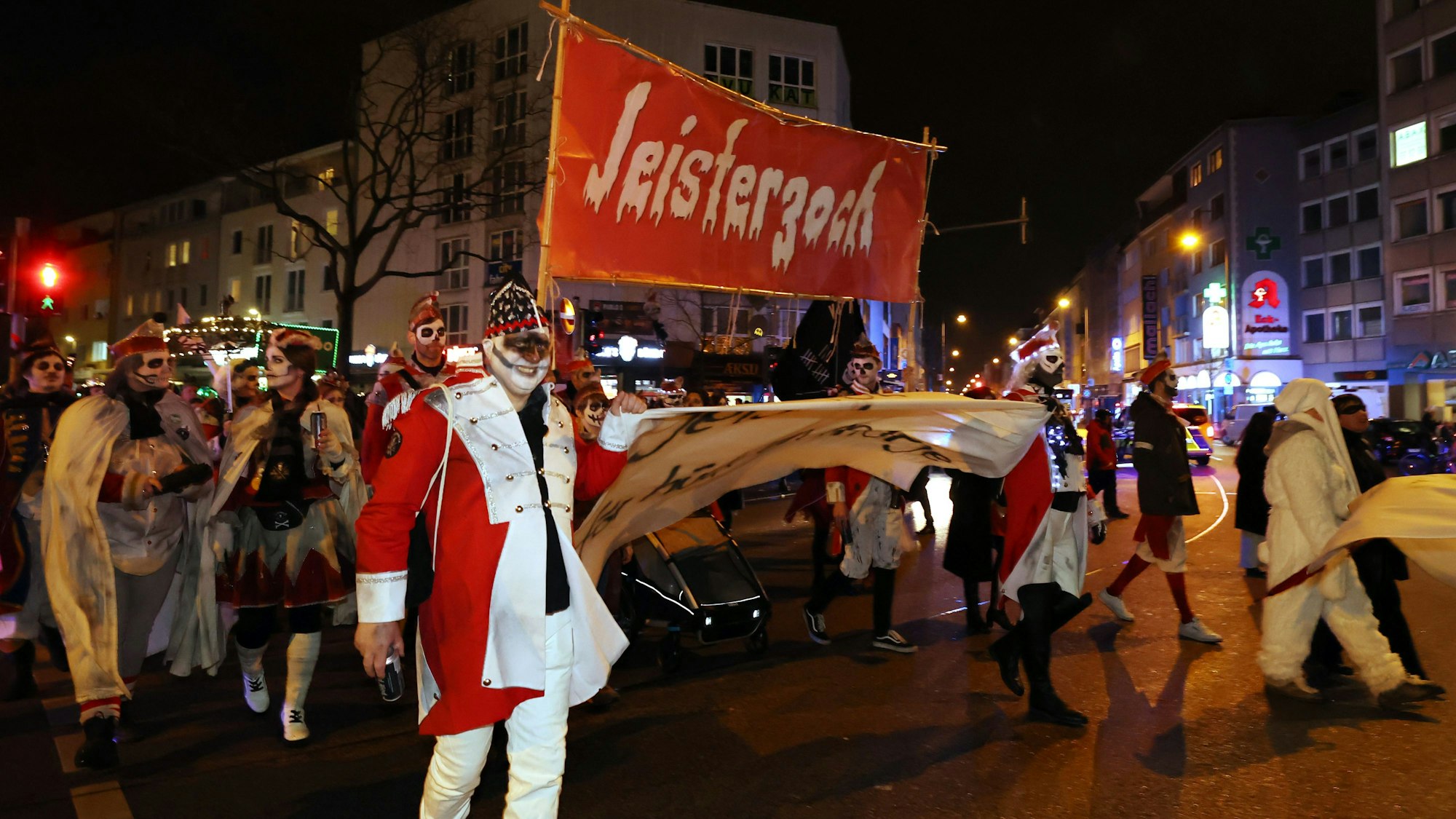 Verkleidete gehen mit einem Plakat auf dem Jeisterzoch steht über eine Straße