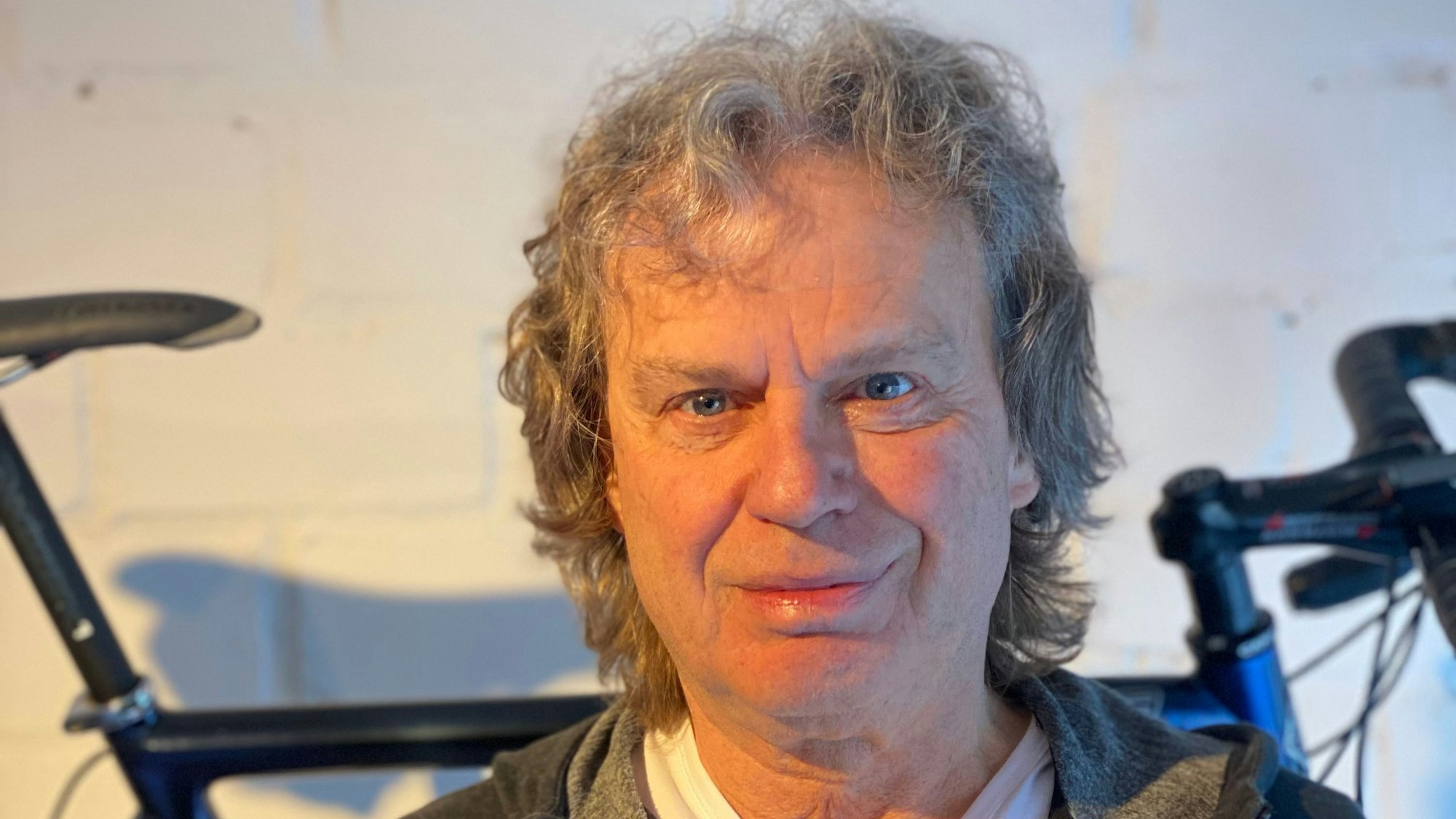 Ein Mann steht vor seinem an der Wand hängenden Rennrad.