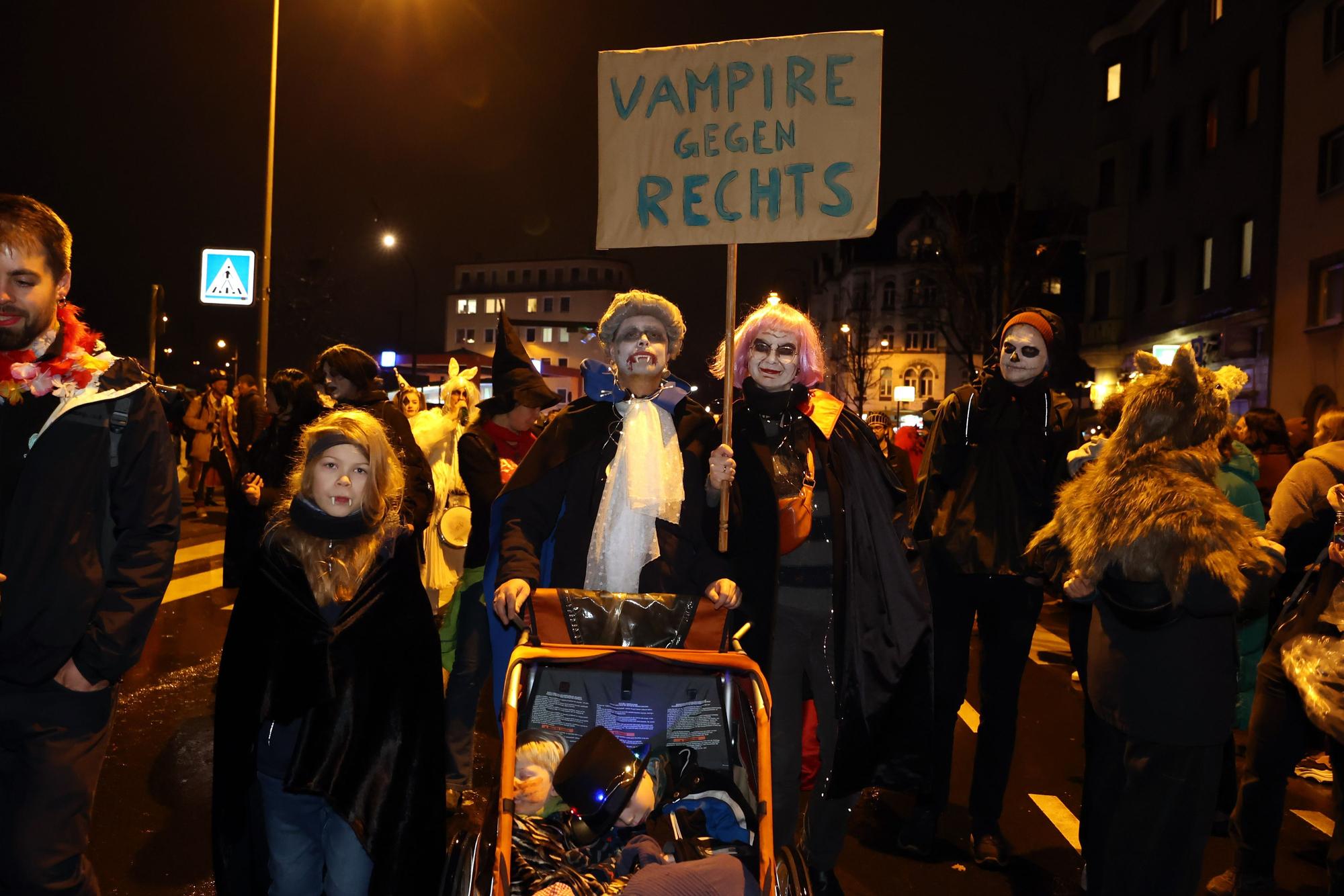 Als Vampire verkleidete Familie hält ein Schild doch mit der Aufschrift "Vampire gegen Rechts"