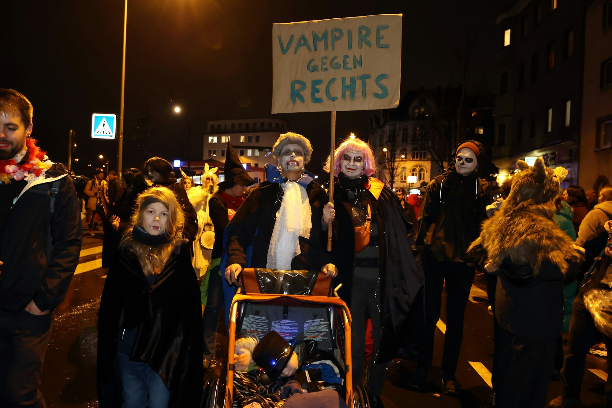 Als Vampire verkleidete Familie hält ein Schild doch mit der Aufschrift "Vampire gegen Rechts"