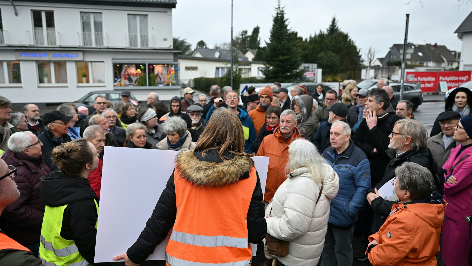 Ein großer Pulk von Menschen steht um die beiden Planerinnen, gekleidet in oranger und gelber Weste herum.