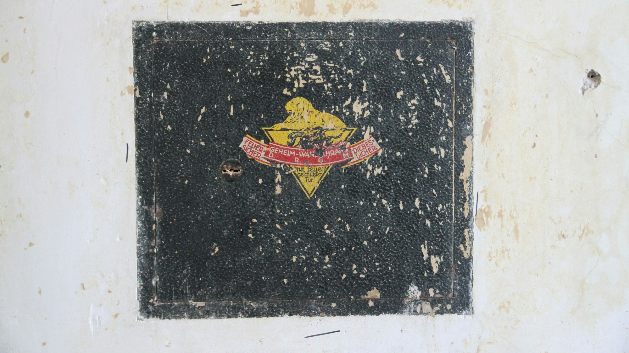 Ein alter Wandtresor mit gelb-rotem Firmenemblem