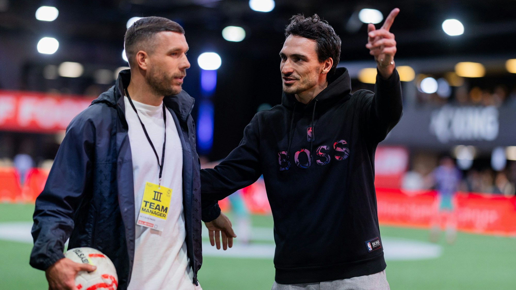 Mats Hummels (r) von Borussia Dortmund, und Lukas Podolski, Präsidenten der ‚Baller League‘, stehen auf dem Spielfeld in der Motorworld.