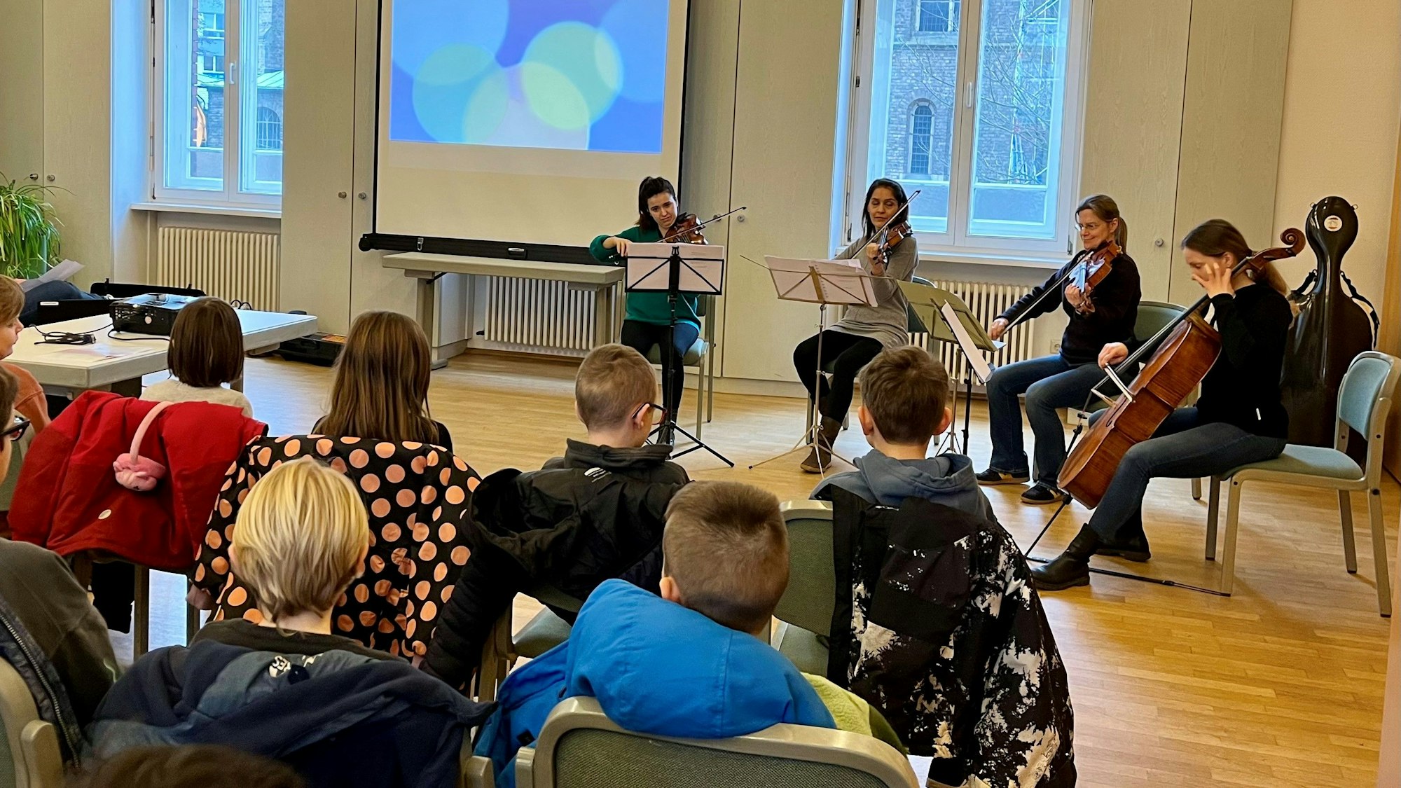 Vier Musikerinnen vor einer Klasse.